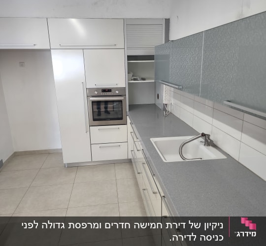 מטבח נקי עם כיור וברז על משטח עבודה אפור